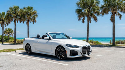 A white SUV car rental driving down a coastal road lined with palm trees in sunny Florida