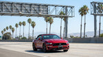 Silver car rental driving under an electronic toll scanner on a sunny California highway