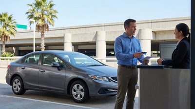 A row of modern vehicles ready for car hire at a sunny airport rental car lot in Houston, Texas