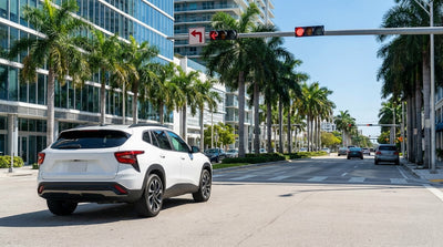 A car rental stopped at a red traffic light on a palm tree-lined street in downtown Miami