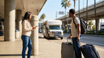 Travelers waiting for a car rental shuttle bus outside the LAX Terminal 5 arrivals area in Los Angeles