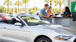 Person inspecting the windscreen and tyres of a white SUV at a car rental parking lot in Orlando