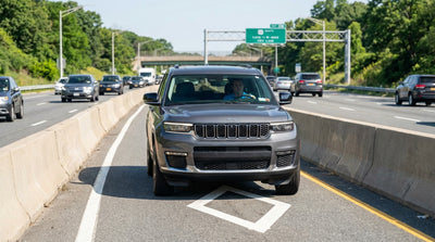 A car hire drives in daytime traffic on the multi-lane Long Island Expressway in New York with HOV lane signs visible