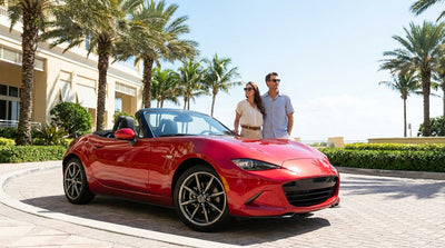 A white convertible car rental drives along a scenic coastal highway in Florida under a sunny blue sky