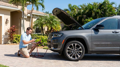 A person looking under the hood of their Florida car hire parked on a sunny, palm-lined street