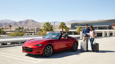 A red convertible car rental driving down the Las Vegas Strip past bright, iconic casino signs at dusk