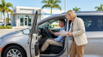 A driver uses adaptive hand controls in a car hire while driving along a sunny coastal road in Florida