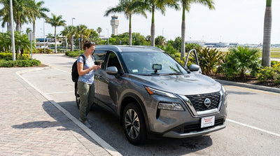 A white car rental pulled over on a sunny street lined with palm trees in Miami