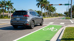 A car rental at a Florida intersection waits at a red light to turn right across a green cycle lane