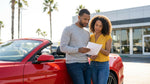 A white car rental driving on a scenic coastal highway in California overlooking the ocean