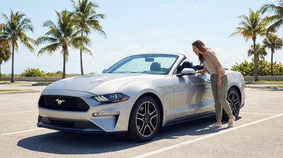 A person refueling their white car rental at a sunny gas station with palm trees in Florida
