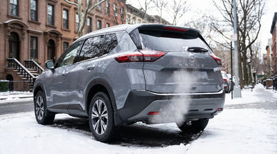A modern car rental idling on a snowy street in New York with exhaust visible in the cold winter air