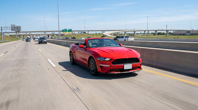 A modern car rental driving under an express lane toll sign on a sunny Texas freeway