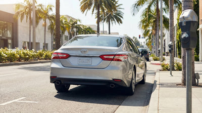A silver car hire parked on a sunny Los Angeles street next to a parking restriction sign