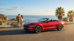 A convertible car rental driving on a scenic highway along the sunny California coast with ocean views