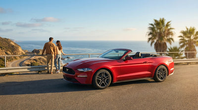 A convertible car rental driving on a scenic highway along the sunny California coast with ocean views