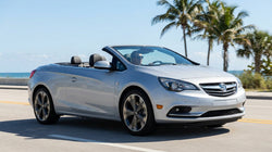 A modern car rental parked on a sunny beach road lined with tall palm trees in Florida