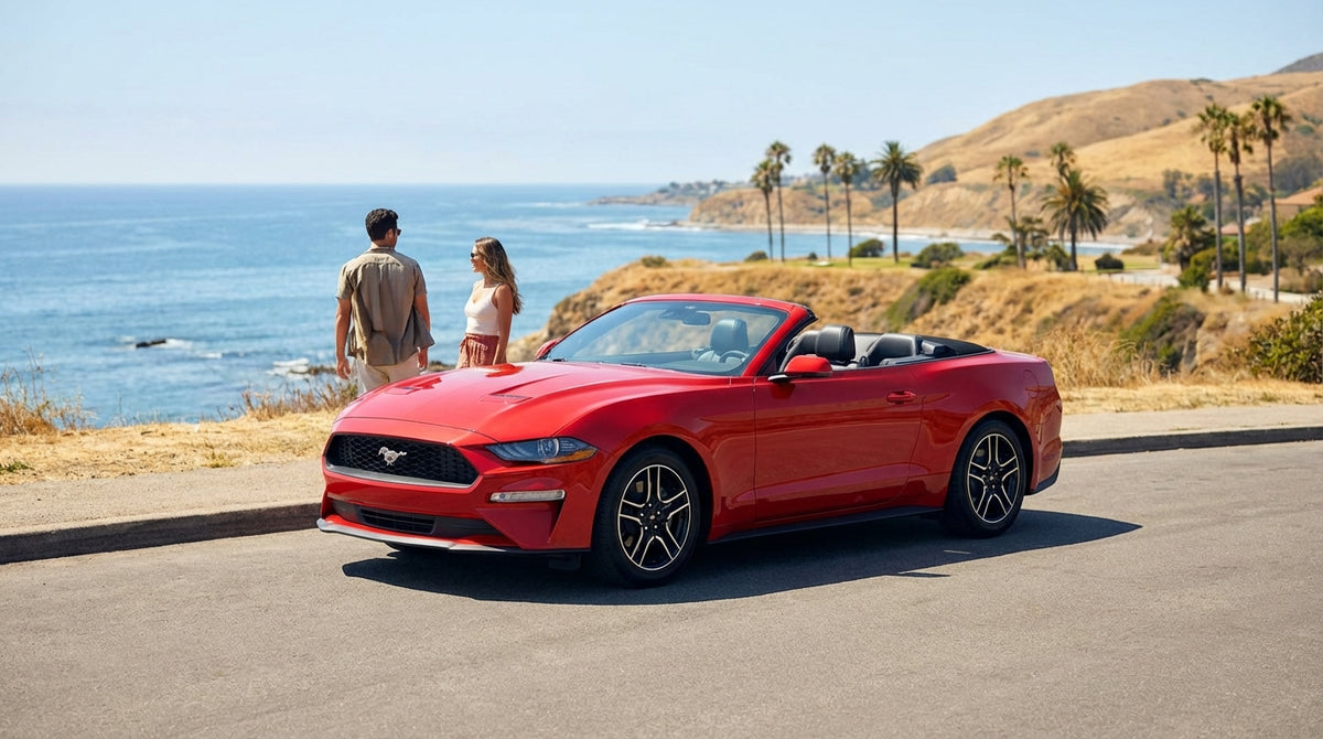 A red Ford Mustang convertible car rental driving down a scenic coastal highway in California