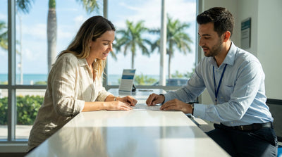 A red convertible car hire driving down sunny Ocean Drive in Miami with colorful Art Deco buildings