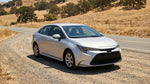 A silver car rental sedan on a dusty, unpaved road in the vast California desert landscape