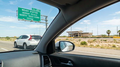 A silver car rental driving on a multi-lane highway past a green road sign in Texas