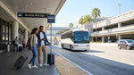 Travelers with luggage waiting for a car hire shuttle bus outside LAX Terminal 7 in Los Angeles