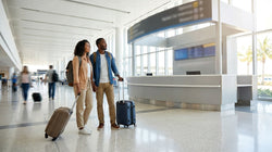 Travelers waiting at the Hola car rental desk inside the Miami airport terminal