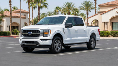 A sedan car rental parked on a sunny street lined with tall palm trees in California