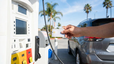 A person's hand holding a credit card at a gas pump payment terminal for their car rental in California