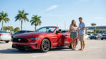 A red convertible car rental driving on a scenic coastal highway in Florida on a sunny day