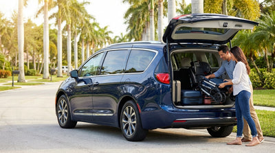 A family with luggage and a pushchair loading their spacious SUV car hire on a sunny day in Orlando