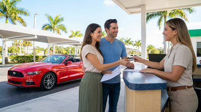A red convertible car hire parked on a sunny Florida road with palm trees and a white sand beach