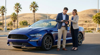 A car rental driving on a sunny, winding coastal highway with ocean views in California