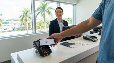 A person making a contactless payment with a smartphone for a car hire at a sunny Orlando rental desk
