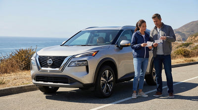 A rental car with its hazard lights on is parked on the side of a scenic desert highway in California