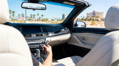 A person plugs a phone into the USB port of a modern car rental on the Las Vegas Strip at dusk
