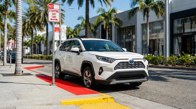 A silver car hire parked beside a bright red curb on a palm-lined street in Los Angeles