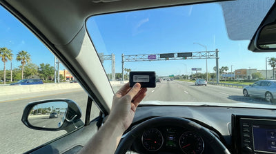 A modern car hire driving on a sunny multi-lane highway with toll signs in Orlando, Florida