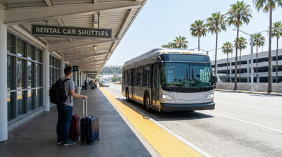Travelers with luggage wait for a car rental shuttle bus outside LAX Terminal 6 in Los Angeles