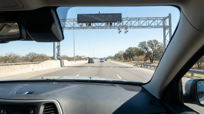 A modern car hire vehicle driving down a wide open toll road in Texas on a sunny day
