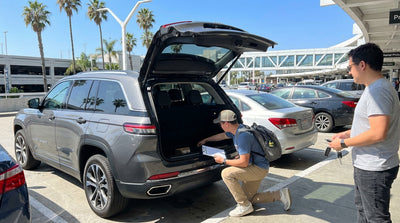 Customer inspecting the interior of their car rental vehicle at a sunny pickup lot in Los Angeles