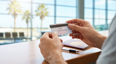 Hands holding a UK driving licence and keys for a car hire on a sunny palm-lined road in Florida