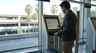 A person with luggage uses a self-service kiosk for their car rental pickup at LAX in Los Angeles