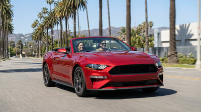 A car rental on a sunny Los Angeles freeway driving towards the iconic Hollywood sign on the hills