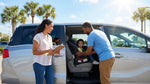 A father installs a child seat into a family car hire vehicle in a sunny Orlando parking lot