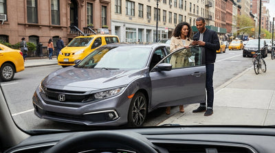 A car rental driving across the Brooklyn Bridge towards the iconic New York City skyline on a sunny day