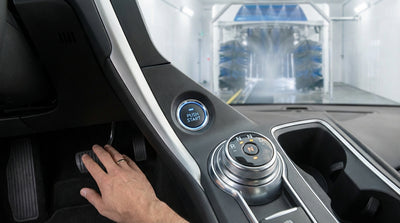 A modern white car rental being pulled through an automatic car wash on a sunny day in California