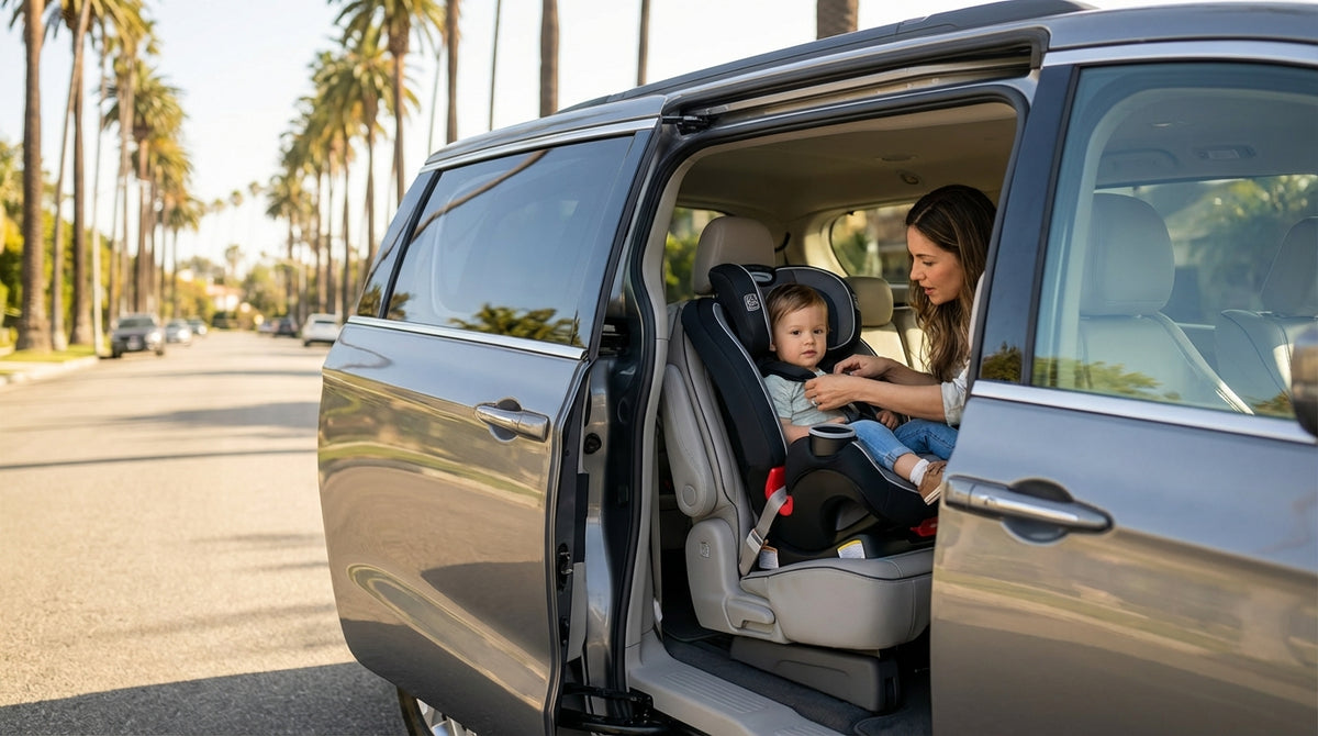 A father fastens his child into a car seat in their family car rental on a sunny street in California