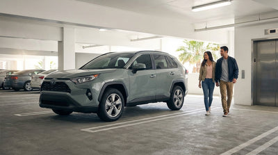 A silver car hire parked on a sunlit street in Los Angeles with tall palm trees