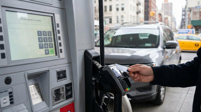 A person refueling a car rental at a gas station pump in New York